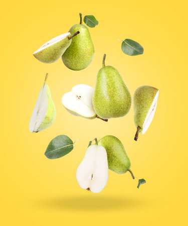 Fresh pears and green leaves on yellow backgroundの写真素材