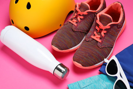 Helmet, sneakers, thermos, and sunglasses on pink backgroundの写真素材