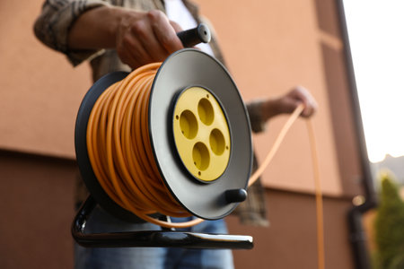 Man with extension cord reel outdoors, closeupの写真素材