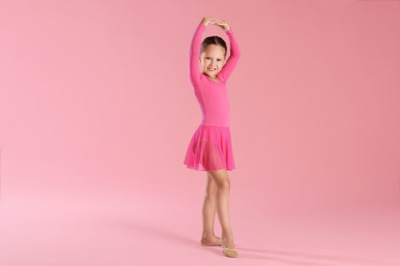 A ballerina practicing dance moves on pink backgroundの写真素材