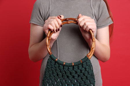 Teenage girl with handmade macrame bag on red background, closeupの写真素材