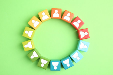 Human resource. Circle of colorful cubes with human icons on light green background, top view