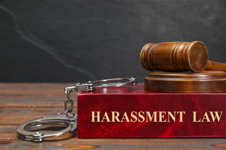 Harassment law book, judge's gavel and handcuffs on wooden table, closeupの写真素材