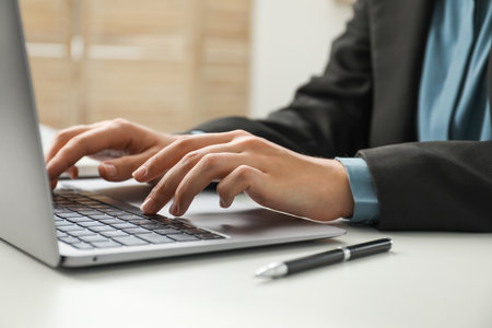 Businesswoman using laptop at white table indoors, closeup. Modern technologyの写真素材