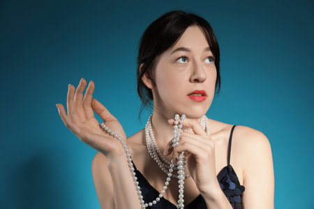 Beautiful young woman with pearl jewelry posing on blue backgroundの写真素材