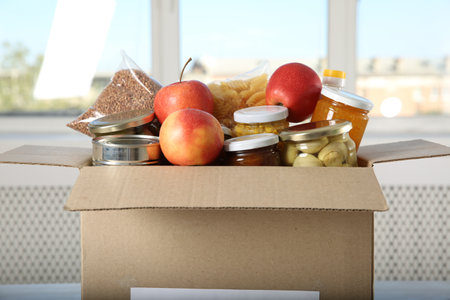 Different food products for donation in box indoors, closeup