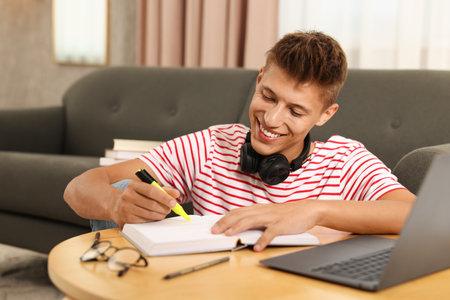 Student with headphones studying at table indoorsの写真素材