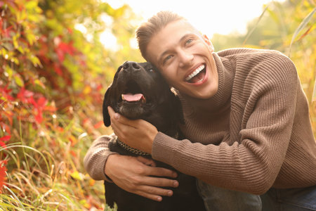 Happy man hugging cute dog outdoors on autumn dayの写真素材