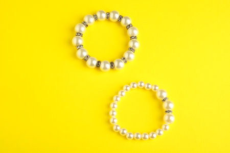 Beautiful bijouterie. Stylish bracelets on yellow background, top viewの写真素材