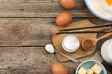 Baking powder in bowl and other products on wooden table, flat lay. Space for textの写真素材