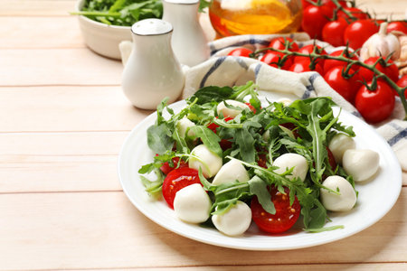 Tasty salad with arugula, spinach, mozzarella cheese and tomatoes on wooden table, closeupの写真素材
