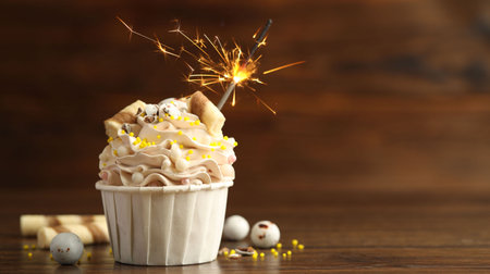 Tasty cupcake with burning sparkler on wooden table, space for textの写真素材