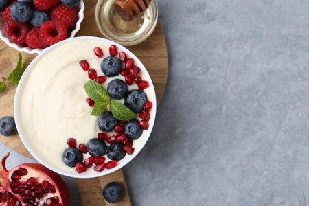 Tasty cooked semolina porridge with berries served on gray table, top view. Space for textの写真素材