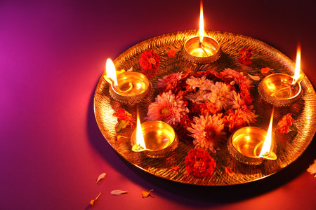Diwali celebration. Diya lamps and beautiful flowers on color backgroundの写真素材