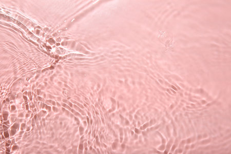Rippled surface of clear water on pink background, top viewの写真素材