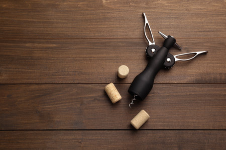 Wing corkscrew and corks on wooden table, flat lay. Space for textの写真素材