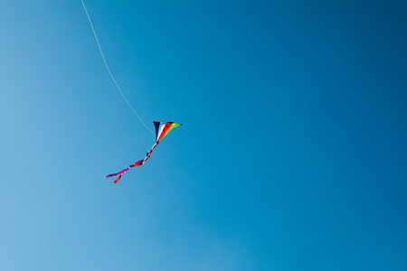 One colorful kite flying in blue sky. Space for textの写真素材