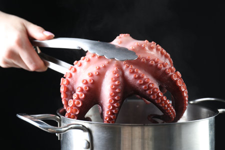 Woman taking boiled octopus from pan on stove, closeupの写真素材