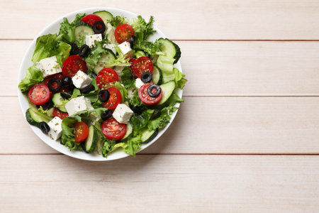 Delicious salad with feta cheese on white wooden table, top view. Space for textの写真素材