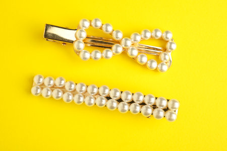 Beautiful bijouterie. Elegant hair clips on yellow background, top viewの写真素材