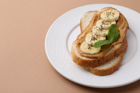 Tasty sandwich with peanut butter, banana, chia seeds and mint on brown background, closeup. Space for textの写真素材