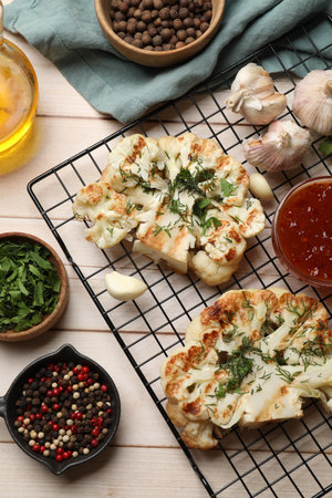 Delicious grilled cauliflower steaks with sauce and spices on wooden table, flat layの写真素材