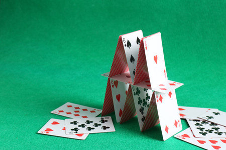 Collapsed house of playing cards on green background. Space for textの写真素材