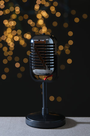 Vintage microphone on table against black background with blurred lights. Sound recording and reinforcementの写真素材