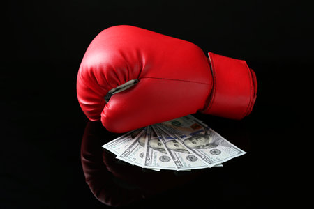 Red boxing glove and dollar banknotes on black mirror surfaceの写真素材