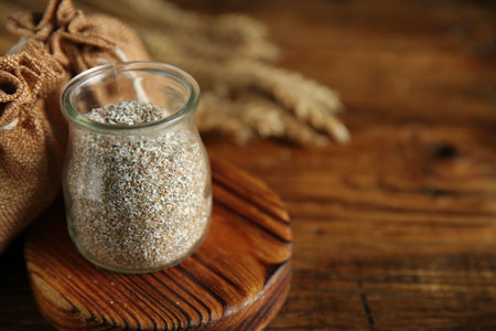 Fresh rye bran in jar on wooden table, closeup. Space for textの写真素材