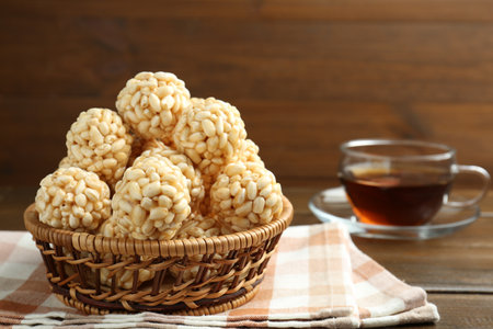Tasty puffed rice balls in wicker basket and tea on wooden table, closeupの写真素材