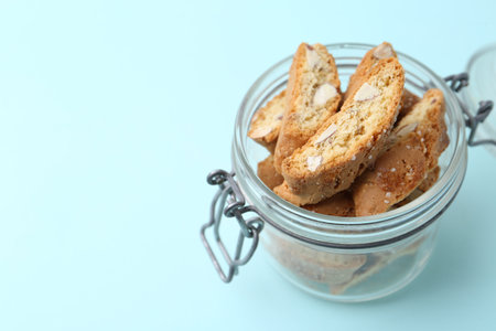 Traditional Italian almond biscuits (Cantucci) in jar on turquoise background, closeup. Space for textの写真素材