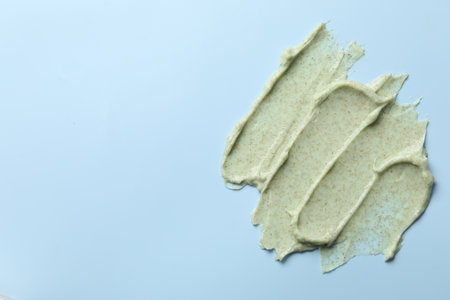 Smears of body scrub on light blue background, top view. Space for textの写真素材
