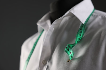 Male mannequin with white shirt and measuring tape on gray background, closeupの写真素材