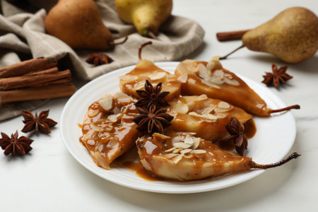 Delicious pears with caramel sauce, almond flakes and anise stars on white table, closeupの写真素材