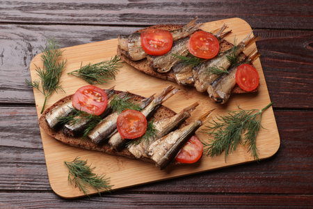 Delicious sandwiches with sprats, dill and tomato on wooden table, top viewの写真素材