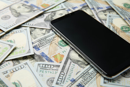 Modern smartphone on dollar bills, closeup viewの写真素材