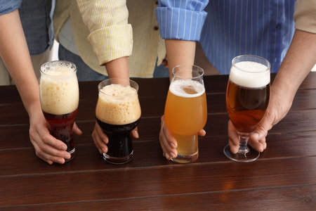 People with different types of beer in glasses at wooden table, closeupの写真素材