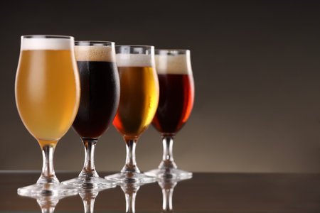 Glasses with different types of beer on mirror surface, closeup. Space for text
