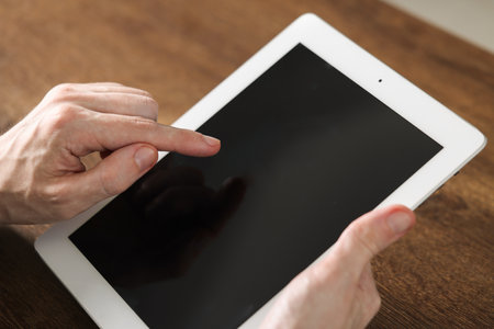 Businessman using tablet at wooden table, closeup. Modern technology