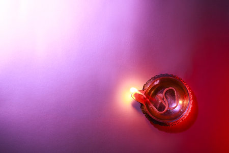 Diwali celebration. Diya lamp on purple background, top view. Space for textの写真素材