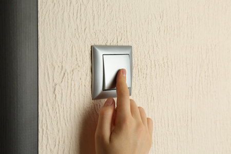 Woman turning light switch on, closeup view