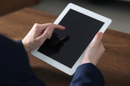 Businessman using tablet at wooden table, closeup. Modern technologyの写真素材