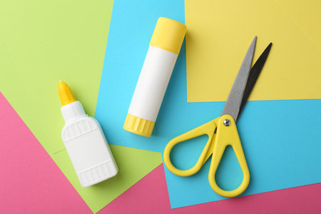 Glue, colorful paper and scissors on pink background, flat layの写真素材