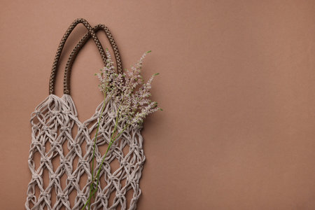 Handmade macrame shopping bag with spikes on brown background, top view. Space for textの写真素材