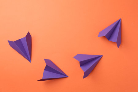 Handmade purple paper planes on orange background, top viewの写真素材