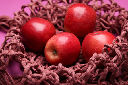 Handmade macrame shopping bag with apples on crimson background, closeupの写真素材
