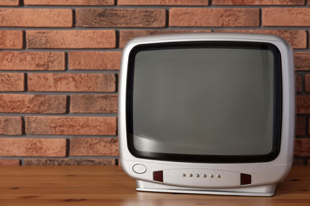 Retro tv set on wooden shelf against red brick wall. Space for textの写真素材