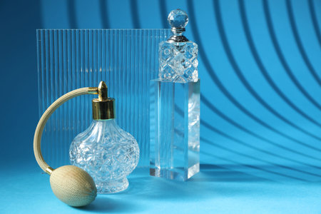 Stylish presentation of perfume bottles on light blue background, space for text