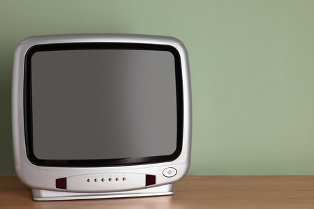 Retro TV set on wooden shelf against green wall. Space for textの写真素材